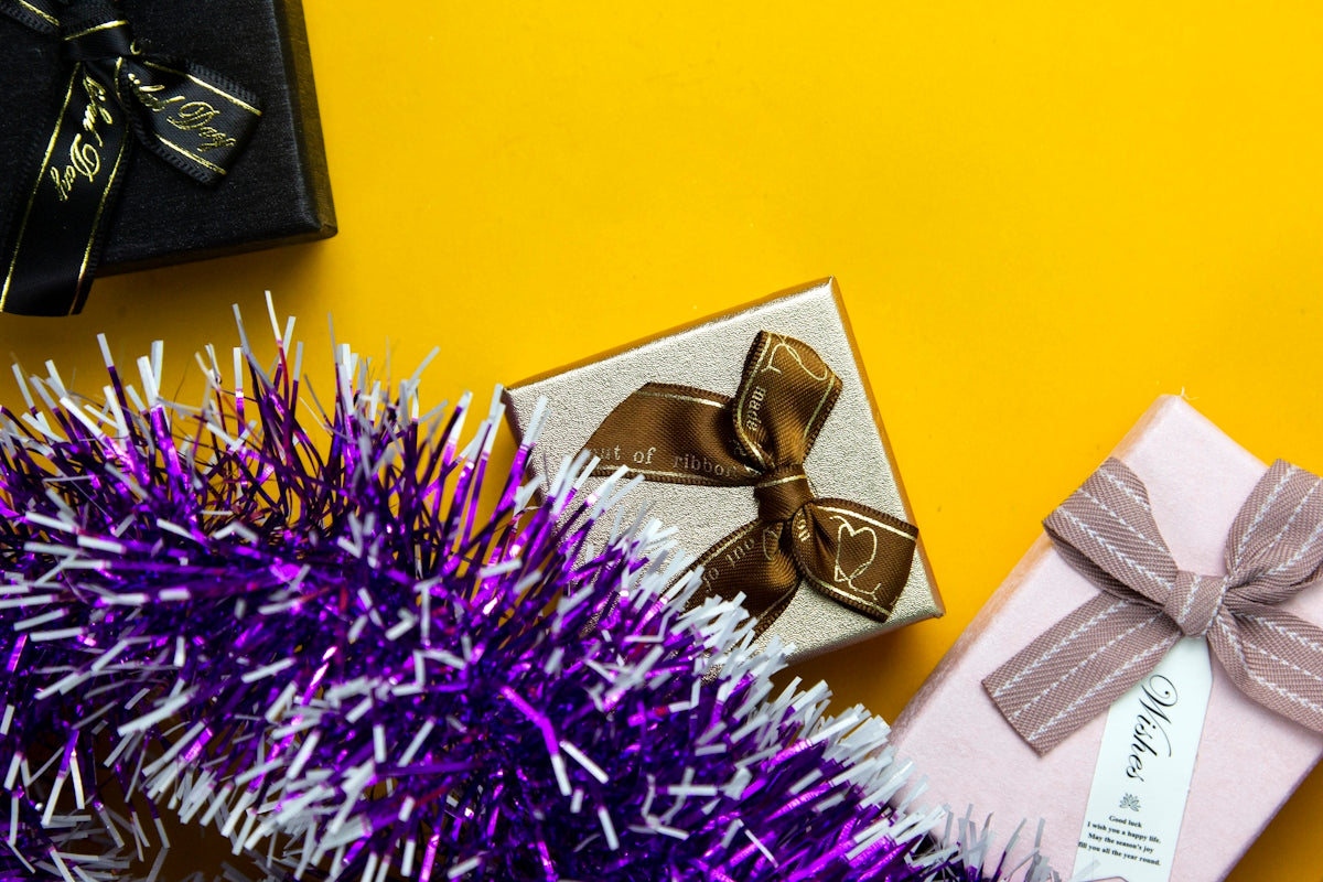 a gift wrapped in gold and silver ribbon next to a purple tinsel