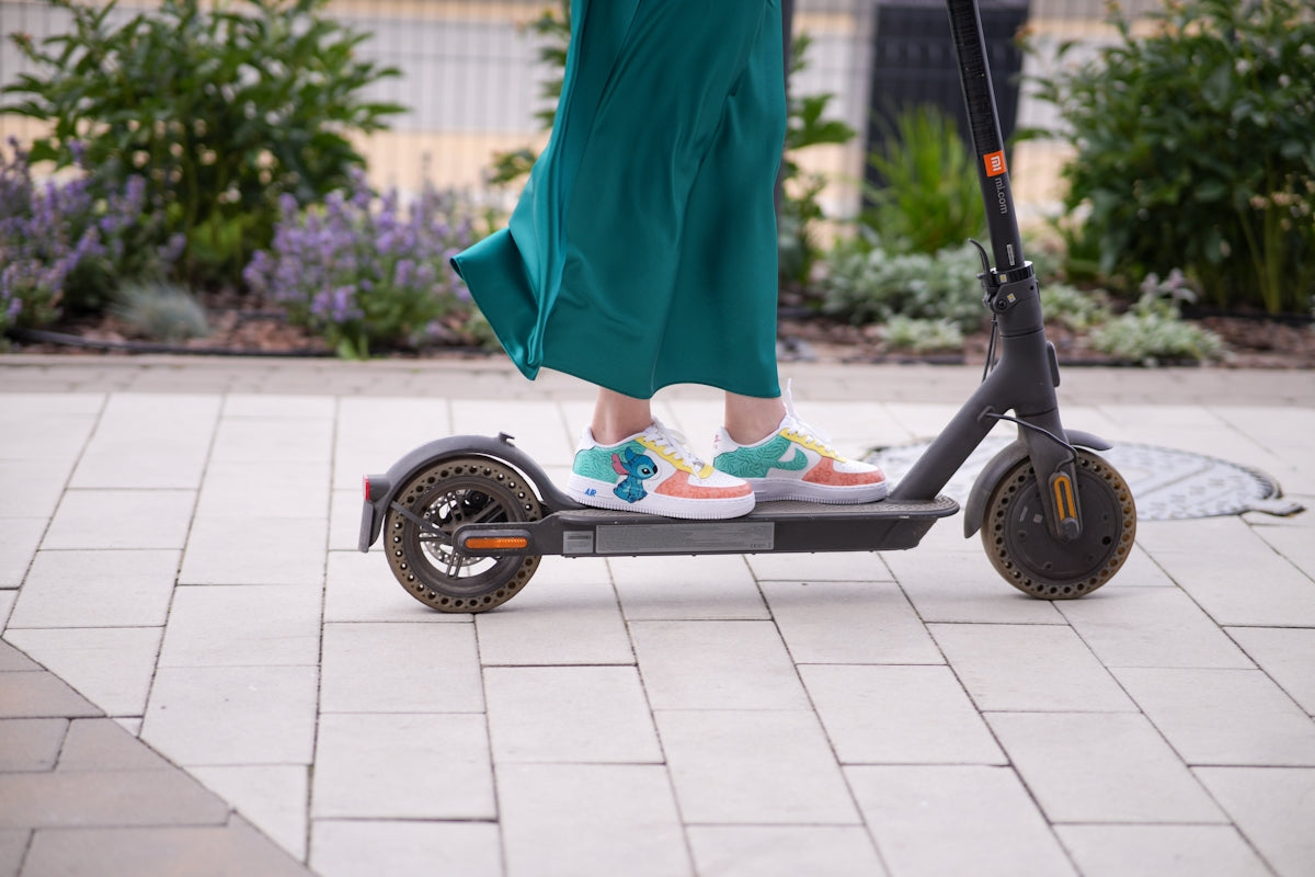 a person standing on a scooter on a sidewalk