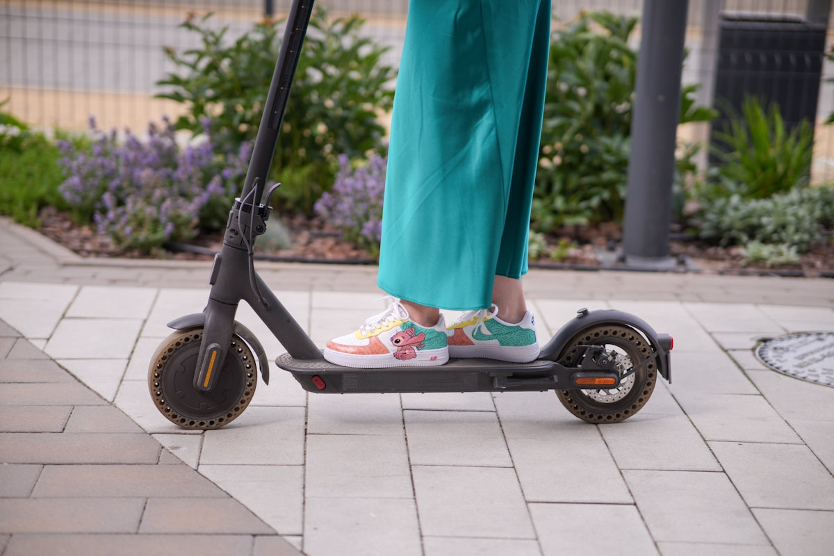 a person standing on a scooter on a sidewalk