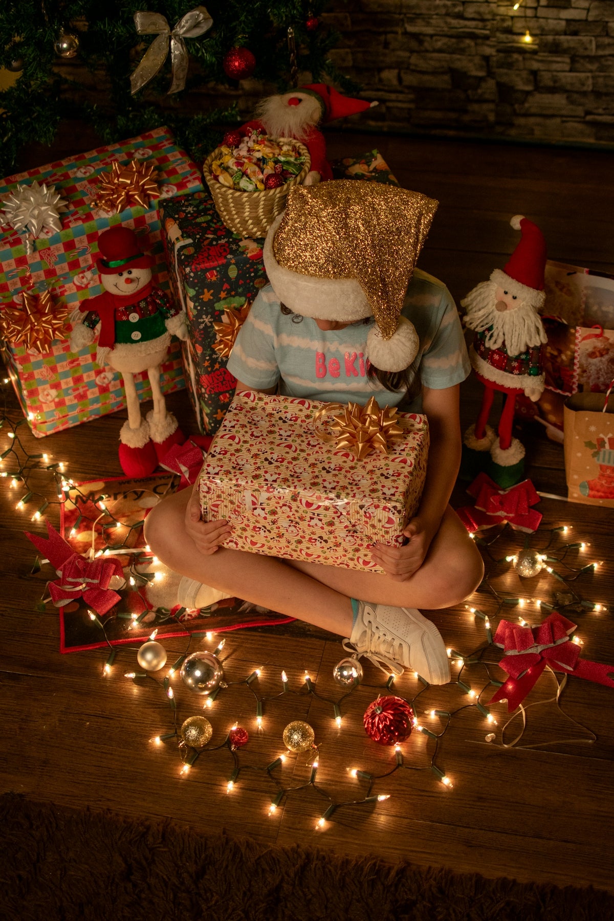 A child sitting on the floor with presents under a christmas tree