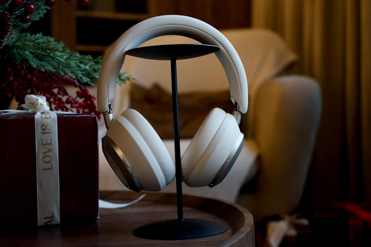 White headphones on a stand next to gift.