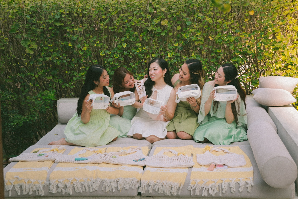 Five women holding white boxes on a couch outdoors