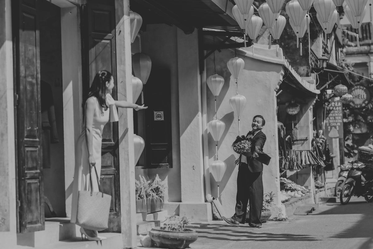 Woman reaches out to man with basket on street.