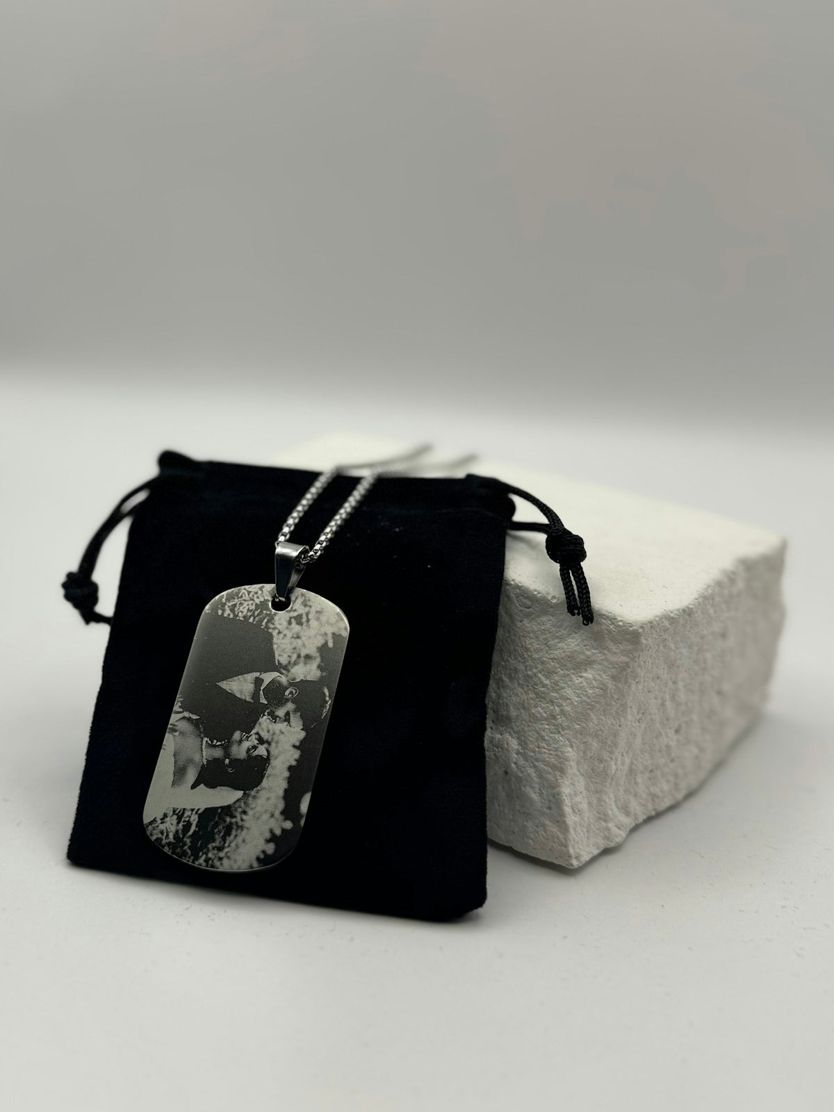 A dog tag necklace rests on a black pouch.