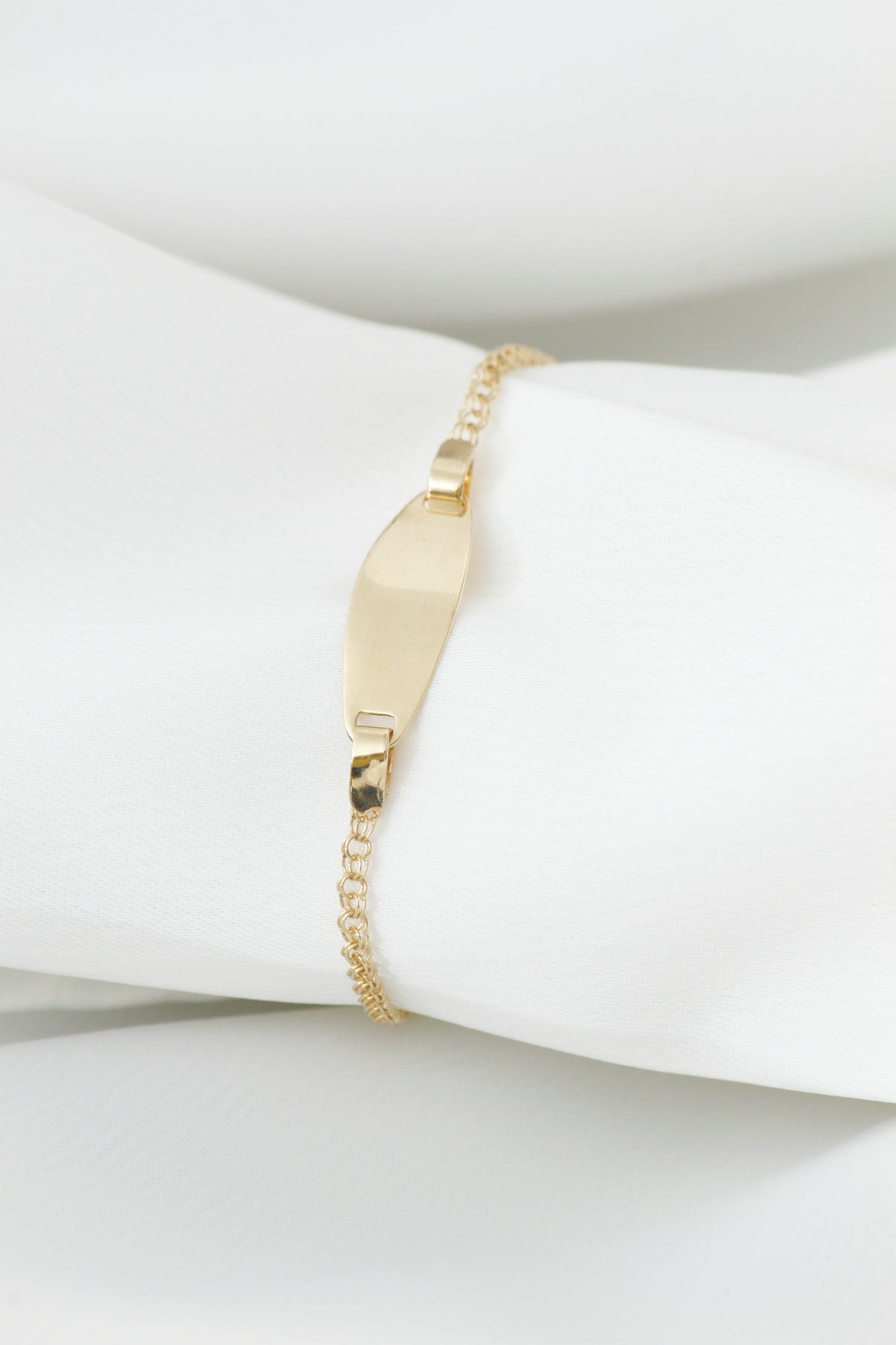 A delicate gold bracelet with an id tag