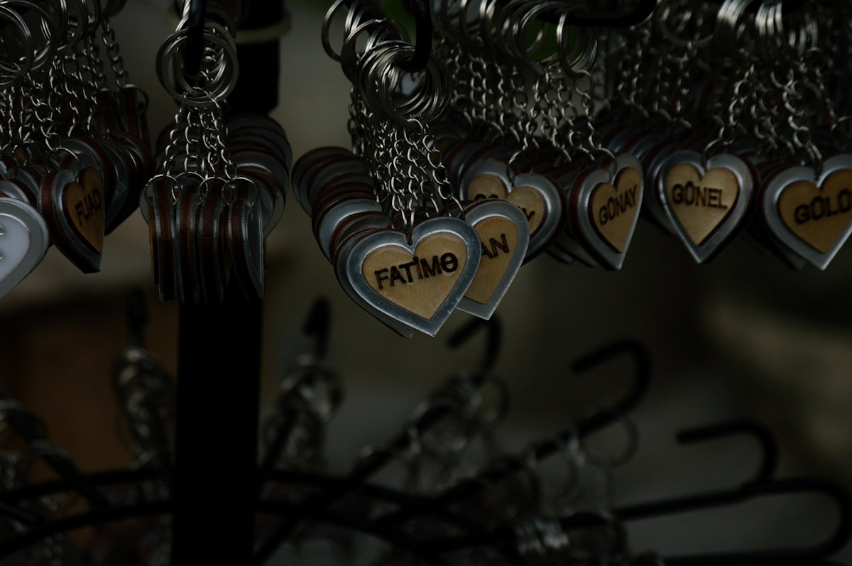 Personalized heart keychains with names displayed on a dark background.